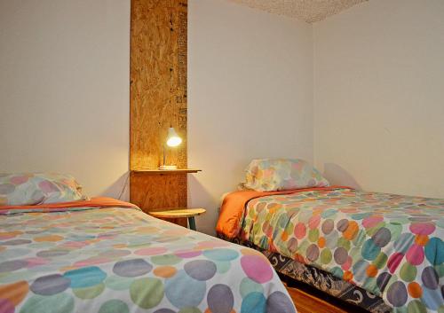 a bedroom with two beds and a table with a lamp at AlterNative Hostels in Cuenca