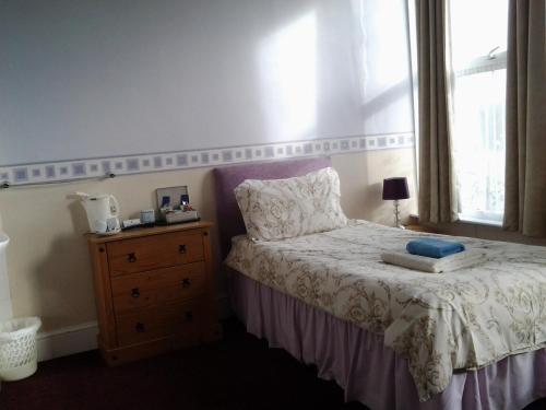 a bedroom with a bed with a dresser and a window at The Mount View Hotel, Bed & Breakfast in Penzance
