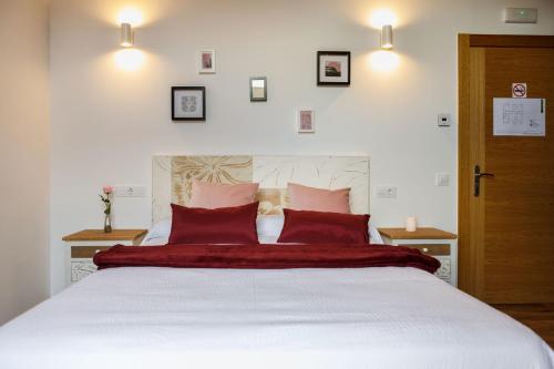 a bedroom with a large white bed with red pillows at Posada rural Fuente Juliana in Barrio de Arriba