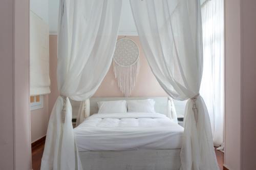 a bed with white curtains in a bedroom at Acropolis Heights at the foot of the Parthenon in Athens