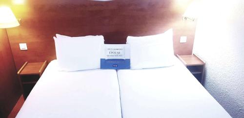 a hotel room with a bed with a book on it at Kyriad Chantilly in Chantilly