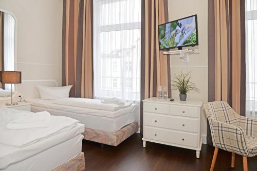 a hotel room with two beds and a tv at Hotel Stralsund in Stralsund