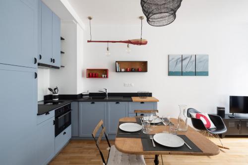 Il comprend une cuisine avec une table et des chaises ainsi qu'une cuisine aux murs blancs. dans l'établissement Le Code 0 by Cocoonr, à Saint-Malo