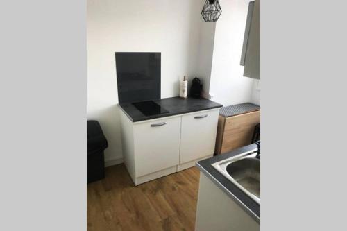 une cuisine avec des armoires blanches et un comptoir noir dans l'établissement Le Convivial Ethnique-Pont Rousseau studio T1bis, à Rezé