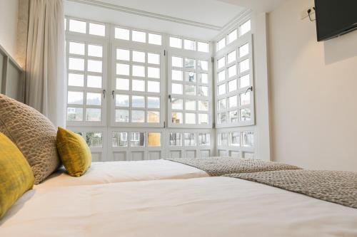 a bedroom with a white bed with a large window at A Casa do Latoneiro in Caldas de Reis