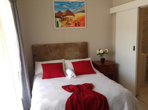a bedroom with a bed with two red pillows at Fomo Lodge in Bellville