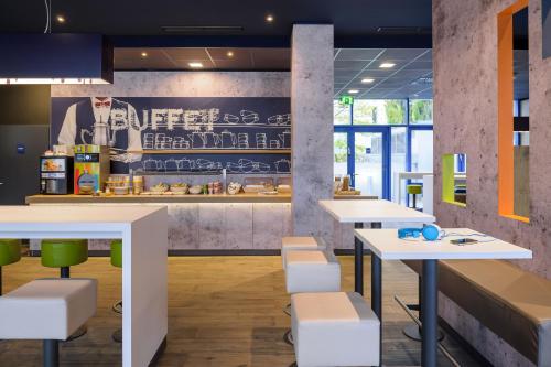un ristorante con tavoli bianchi e sedie verdi di Ibis budget Wien Sankt Marx a Vienna