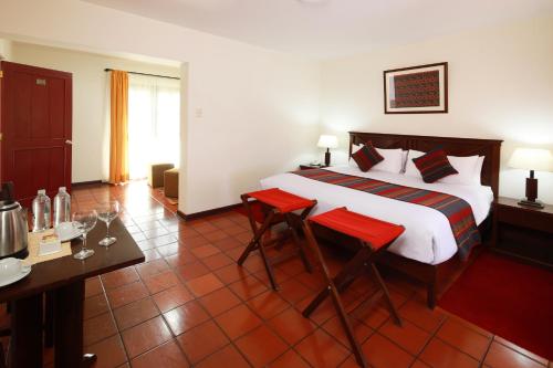 ein Hotelzimmer mit einem Bett, einem Tisch und Stühlen in der Unterkunft Hotel San Agustin Urubamba in Urubamba