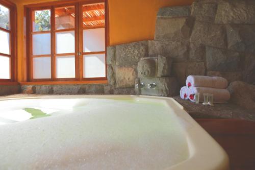 a large bath tub in a bathroom with a stone wall at Hotel San Agustin Urubamba in Urubamba