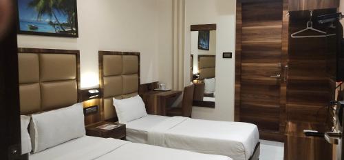 Habitación de hotel con 2 camas y espejo en Hotel Meriton, en Bombay
