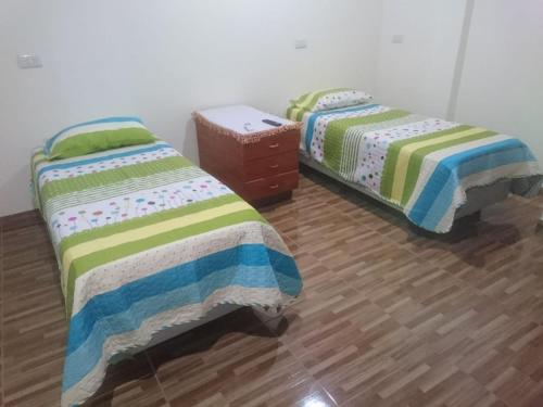 two beds in a room with wooden floors at Alojamiento de la ABU in Puerto Iguazú