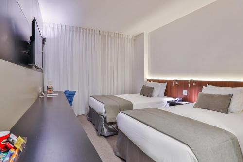 a hotel room with two beds and a flat screen tv at Wyndham Garden Ribeirão Preto Convention in Ribeirão Preto