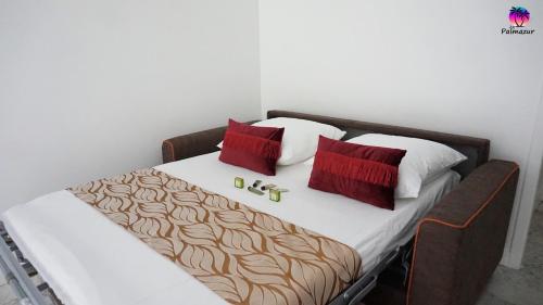 uma cama com almofadas vermelhas e brancas em Proche Croisette, Exclusivité Congres by Palmazur em Cannes