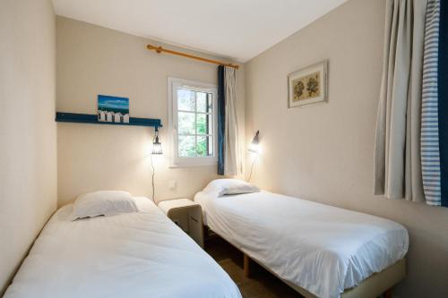 two twin beds in a room with a window at Village Pierre & Vacances Moliets in Moliets-et-Maa