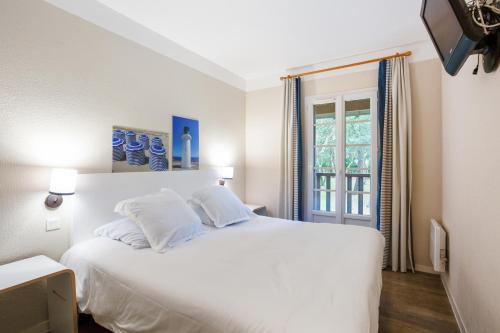 a white bed in a room with a window at Village Pierre & Vacances Moliets in Moliets-et-Maa