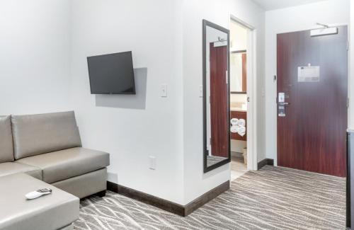 a living room with a couch and a mirror at Cobblestone Hotel & Suites - Janesville in Janesville