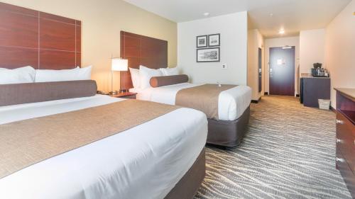 a hotel room with two beds and a television at Cobblestone Hotel & Suites - Janesville in Janesville