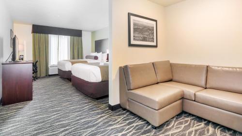a hotel room with a couch and a bed at Cobblestone Hotel & Suites - Janesville in Janesville