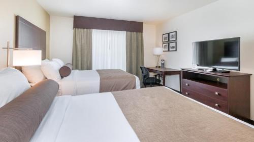 a hotel room with two beds and a flat screen tv at Cobblestone Hotel & Suites - Janesville in Janesville