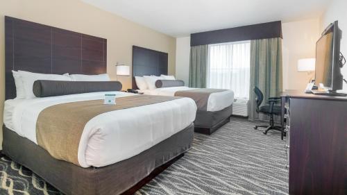 a hotel room with two beds and a television at Cobblestone Hotel & Suites - Janesville in Janesville