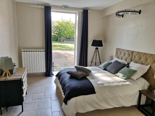 um quarto com uma cama grande e uma janela em La Ferme de Valeuse em Morienval