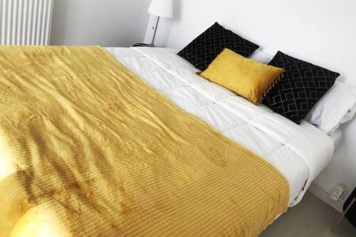 - un lit avec une couverture jaune et des oreillers noirs dans l'établissement Tout en Élégance - Pont Rousseau (Nantes), à Rezé