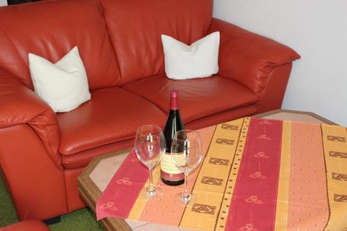 a red couch with two glasses of wine on a table at Birkenhof Pension mit Herz in Pfronten