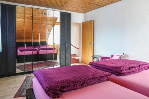 two beds in a room with purple sheets at Haus Sonnboden in Andermatt