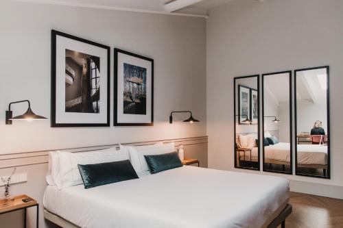 um quarto com uma grande cama branca com 3 espelhos emoldurados em Helen Berger Boutique Hotel em Valência