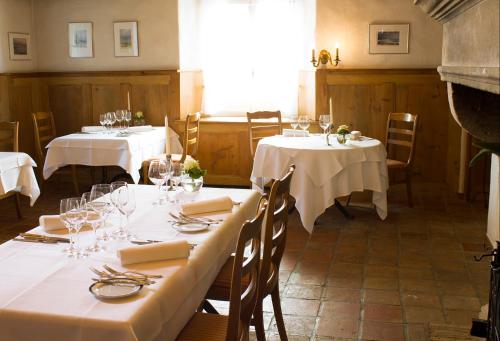 ein Esszimmer mit 2 Tischen und weißen Tischdecken in der Unterkunft Hôtel-Restaurant du Cerf in Sonceboz