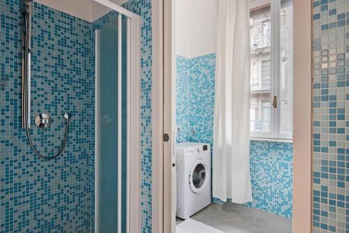 bagno piastrellato blu con lavatrice di Gorgeous flat in the Design District a Milano