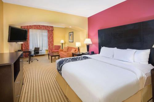 a hotel room with a large bed and a living room at La Quinta by Wyndham Atlanta Union City in Union City