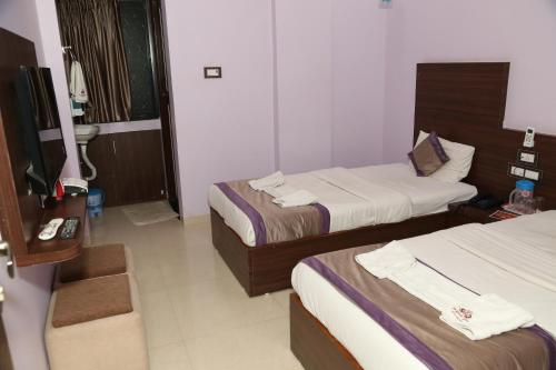 ナーグプルにあるHotel Sai Guest Houseのベッド2台とシンク付きのホテルルームです。