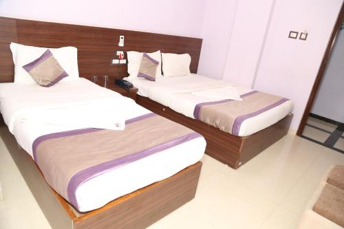 two beds in a hotel room withskirts at Hotel Sai Guest House in Nagpur