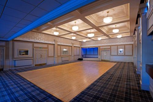 an empty ballroom with a large wooden dance floor at The Corner House Hotel in Annan