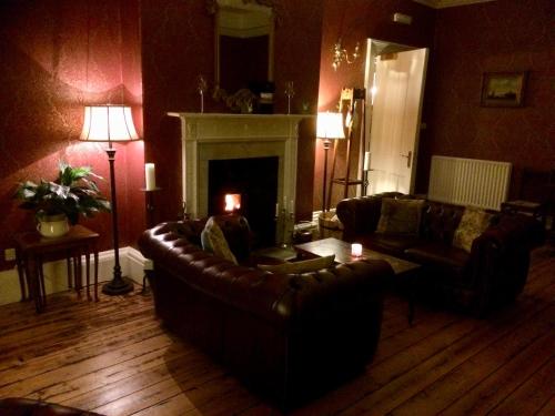 a living room with a leather couch and a fireplace at Otterburn Castle in Newcastle upon Tyne