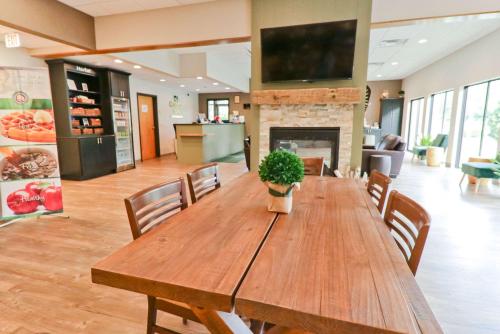 a large wooden table with chairs and a fireplace at Quality Inn Shelburne - Burlington in Burlington