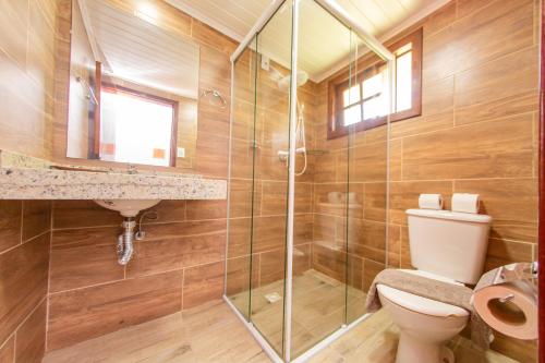 a bathroom with a toilet and a glass shower at Pousada Colina Verde in Garopaba
