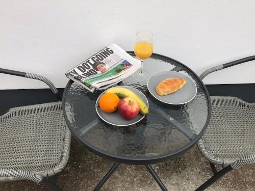 een tafel met een fruitschaal, een krant en een glas sap bij Talland Studio in St Ives
