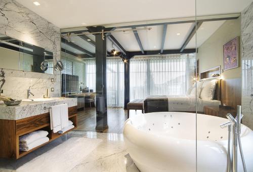 a large bathroom with a tub and a bedroom at Tomtom Suites in Istanbul