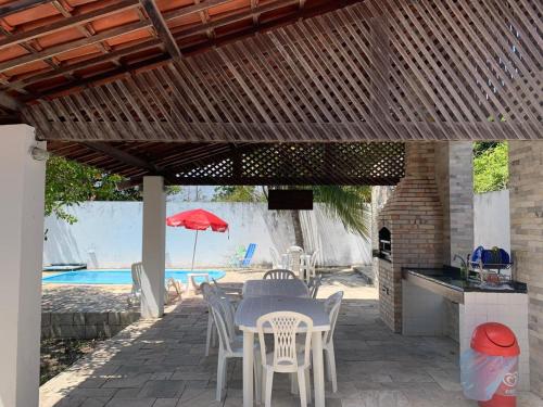 un patio con mesa, sillas y sombrilla en Casa de praia em Carapibus en Jacumã