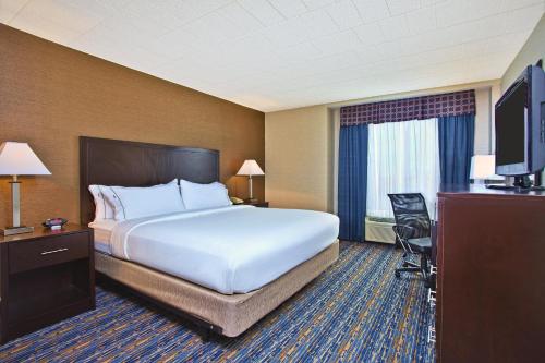 a hotel room with a bed and a television at Holiday Inn Express and Suites Pittsburgh West Mifflin by IHG in West Mifflin
