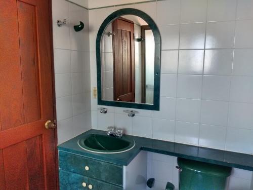baño con lavabo verde y espejo en Hospedaje Casa Marsella en Villa de Leyva