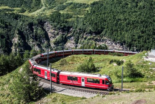 a red train is on the tracks on a mountain at Hotel Bed & Rooms , Corte Rossa -1 Min Walk To Bernina Express in Tirano