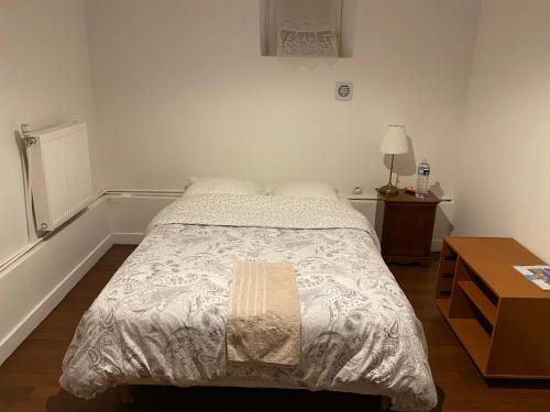 um quarto com uma cama e uma mesa com um candeeiro em Lalanie em Savigny-sur-Orge