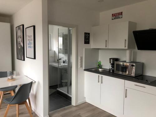 a kitchen with white cabinets and a table and a microwave at Deluxe Apartments Messe Flughafen in Leinfelden-Echterdingen