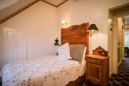a bedroom with a bed with a wooden headboard and a table at The Campbell House Inn in Eugene
