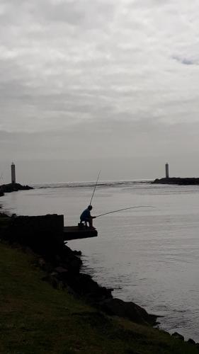 a man sitting on a boat in the water fishing at Casa de praia in Passo de Torres