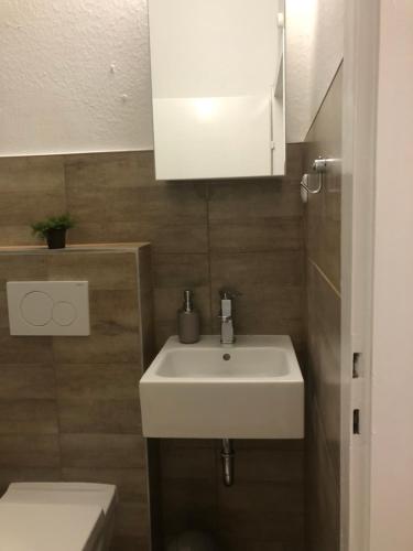 ein Badezimmer mit einem weißen Waschbecken und einem WC in der Unterkunft Super Lage, neu renovierte, gemütliche Unterkunft in Lübeck