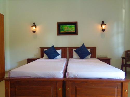 two twin beds in a room with lights on the wall at New Holiday Reach in Unawatuna